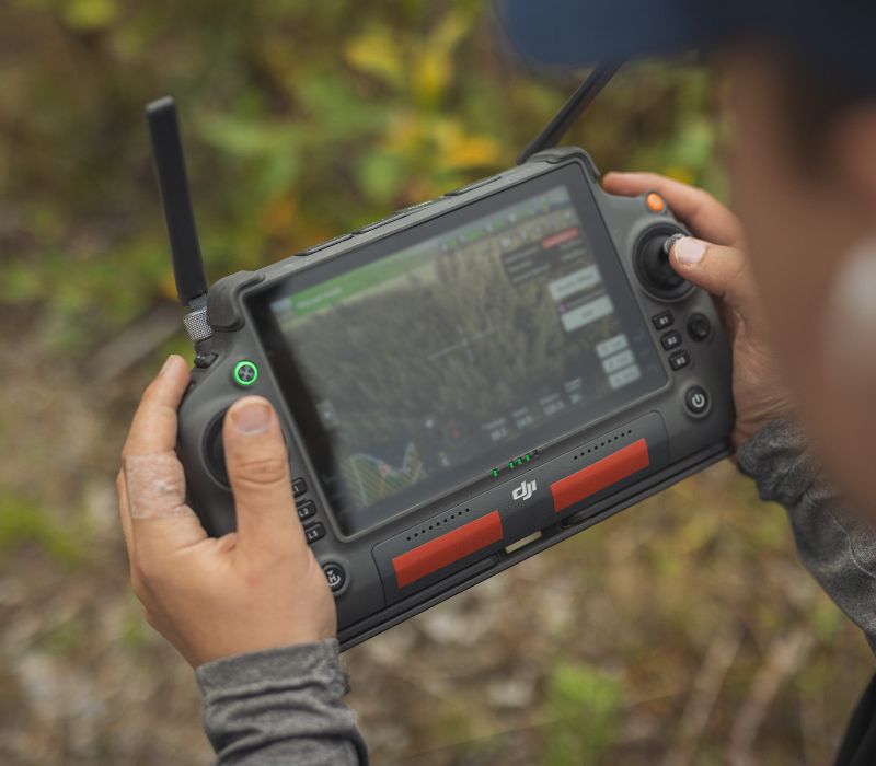 Silvadronesin droonilannoituksen ammattilainen ohjaa lannoitusdroonia suurella DJI-ohjaimella.